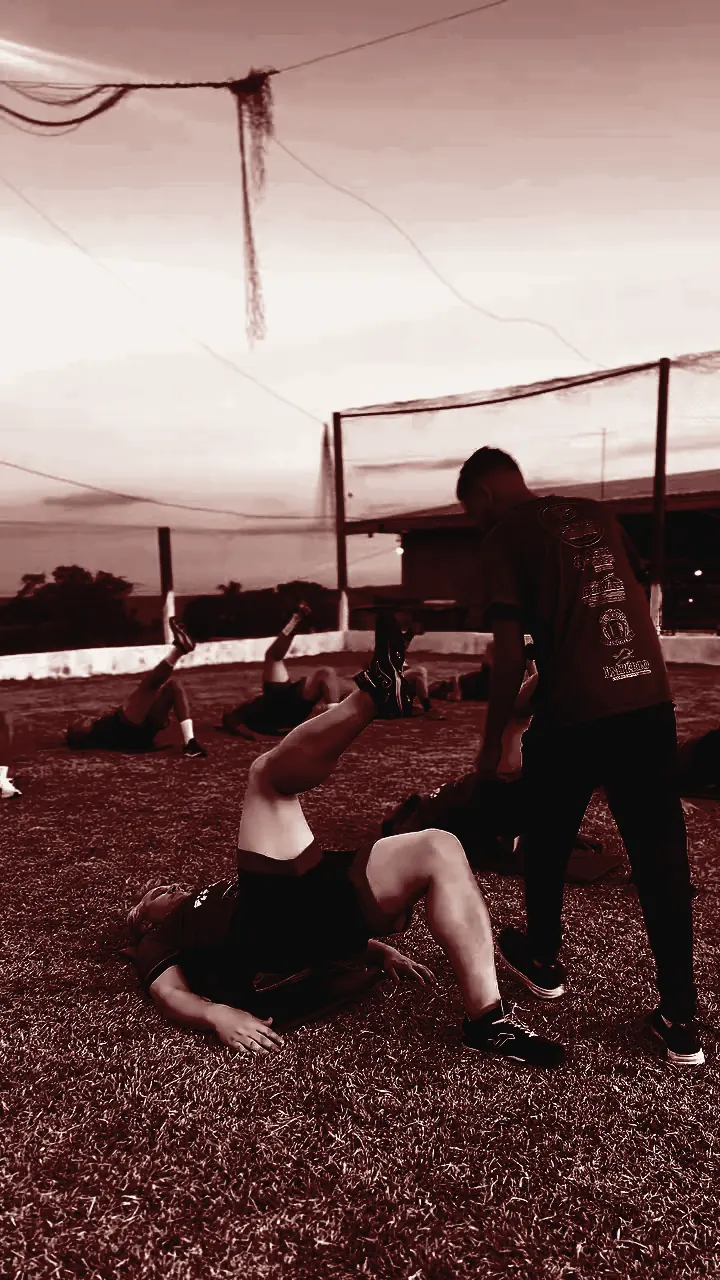 Profissional da GB Sports ajudando atleta em exercício de mobilidade no campo
