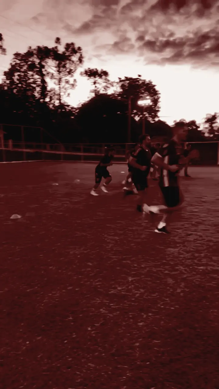 Atletas correndo no campo ao pôr do sol